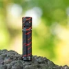 Olightの赤と黒の迷彩柄ハンディライトBaton 3を岩の上に垂直に立たせた正面クローズアップ写真。アウトドアやキャンプでの使用に最適な防水・防塵仕様のコンパクトな高輝度LED懐中電灯。