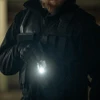 警備員が戦術ベストとグローブを着て懐中電灯を持っている