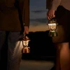 Olightの銅と緑色のOlantern Classic 2 Proランタンを屋外で夜間照明として使用する様子を捉えた遠景です。