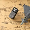 戦闘機の設計図と模型に囲まれたミリタリーデザインのグレーのOlight Oclip Proクリップライト、3つのLED光源と頑丈な金属ボディが特徴のEDCやアウトドア向け防災ミニライト