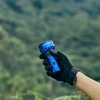 手袋をした手がOLIGHTブルー懐中電灯を持って森の風景を眺めている