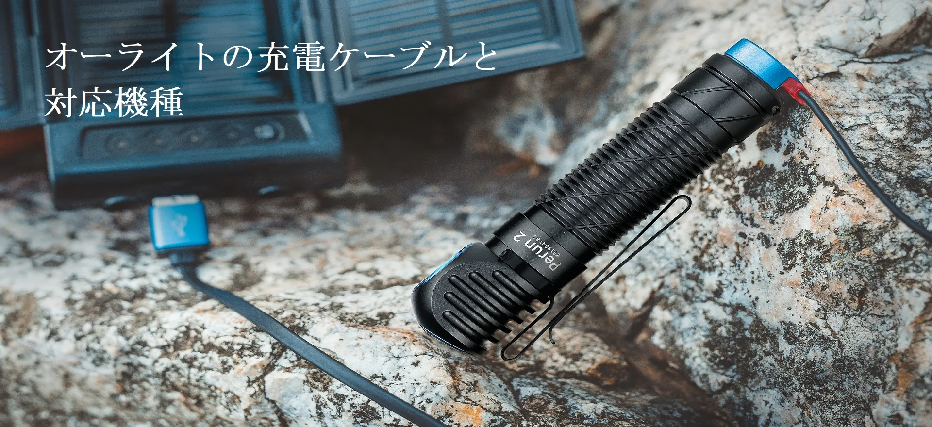 オーライトの懐中電灯と充電ケーブルが岩の上に置かれたアウトドアシーン。