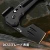 岩の上に置かれたHX OUTDOORSの黒いDC53鋼製タクティカルアックスのブレード表面