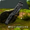 グローブをはめた手で持つ、滑り止め加工が施された黒いG10ハンドルのタクティカル折りたたみナイフ