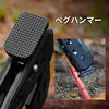 キャンプ用の黒いペグハンマーの打撃面と赤いペグを地面に打ち込む使用シーン