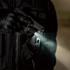 懐中電灯付きの銃を構えた戦術的なベストを着た人