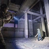 廃墟の建物で懐中電灯を構えるタクティカルギアの男性と、懐中電灯を持ったもう一人の男性。