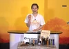 Olightのオレンジ色Oclip Pro Sを手に持ち紹介する女性スタッフと様々なオーライト懐中電灯が並ぶ新製品発表会の様子