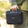 男性がOlightの頑丈な黒い保護ケースを屋外で持ち運んでいる様子。