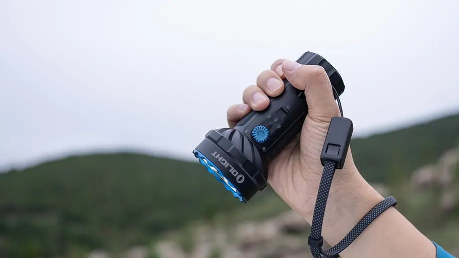 Olight懐中電灯を掴む手。アウトドア、キャンプ、ハイキングに最適なLEDフラッシュライト。