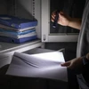 手で文書を懐中電灯で照らす男のSEO画像。事務室、棚、フォルダー。