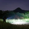 暗闇の山道で懐中電灯を持つバックパッカー